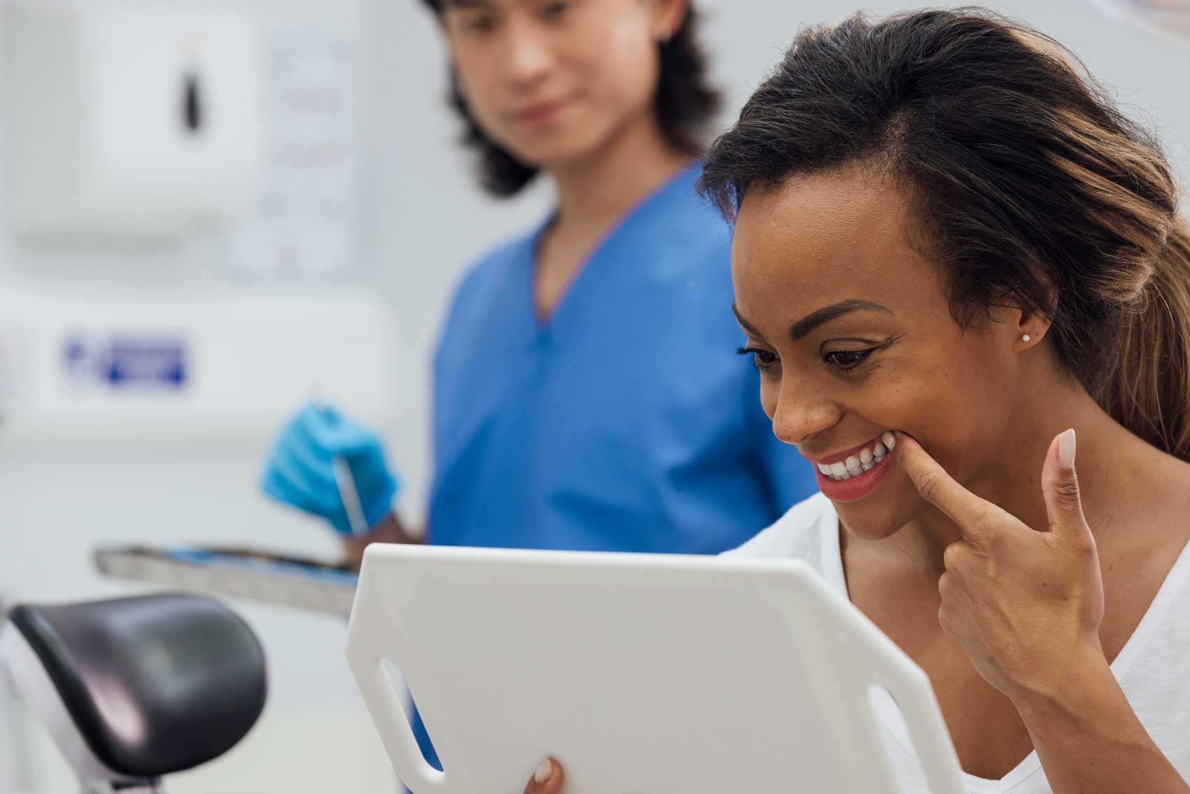woman checking her cosmetic teeth in the mirror at the dental practice