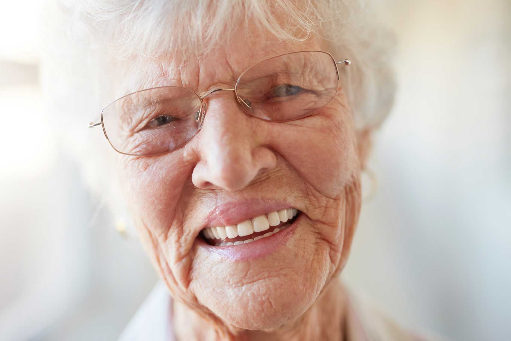 Old woman laughing showing her dental implants.