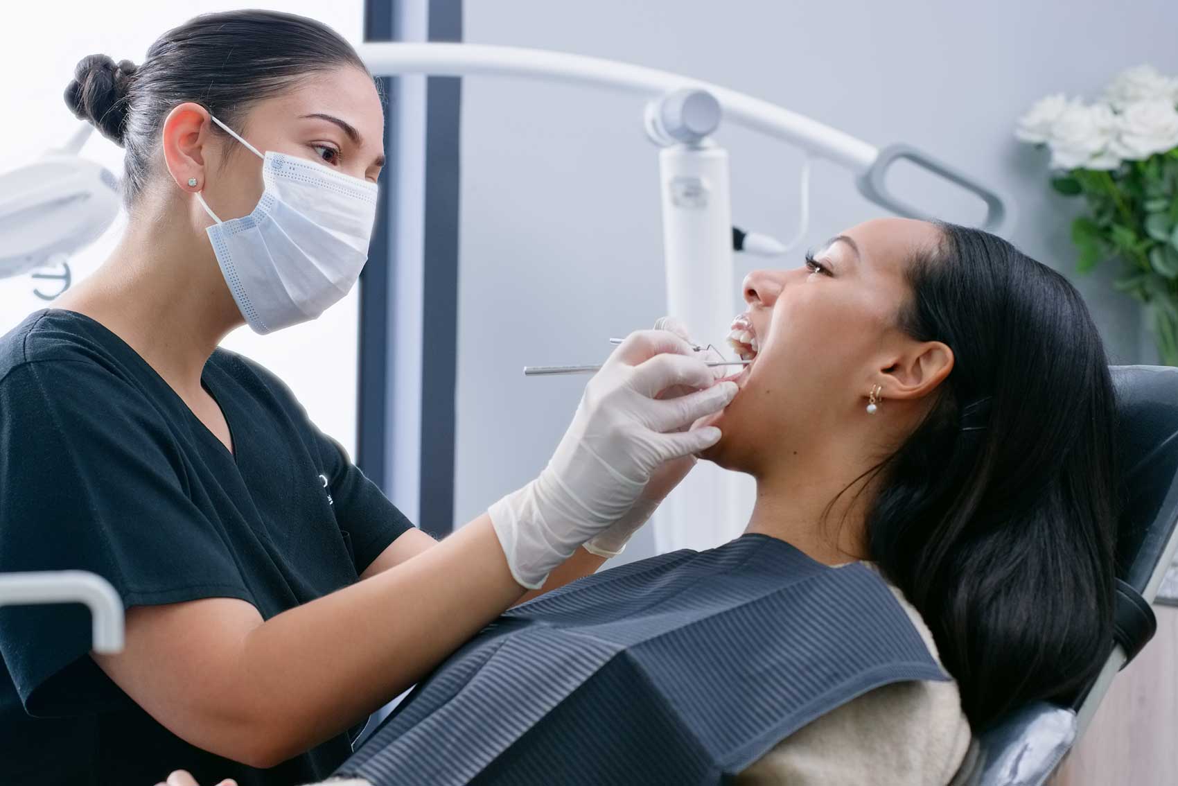 Dentist conducting general checkup on a female patient who is lying on a chair